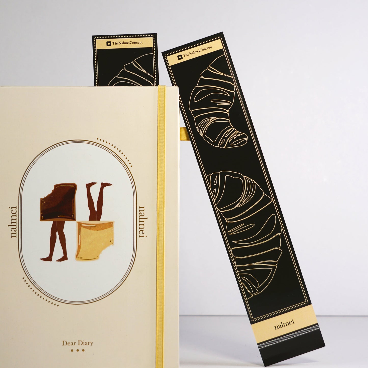 A large black book mark with croissant illustrations | a bookmark leaning on a quotes journal | Nalmei