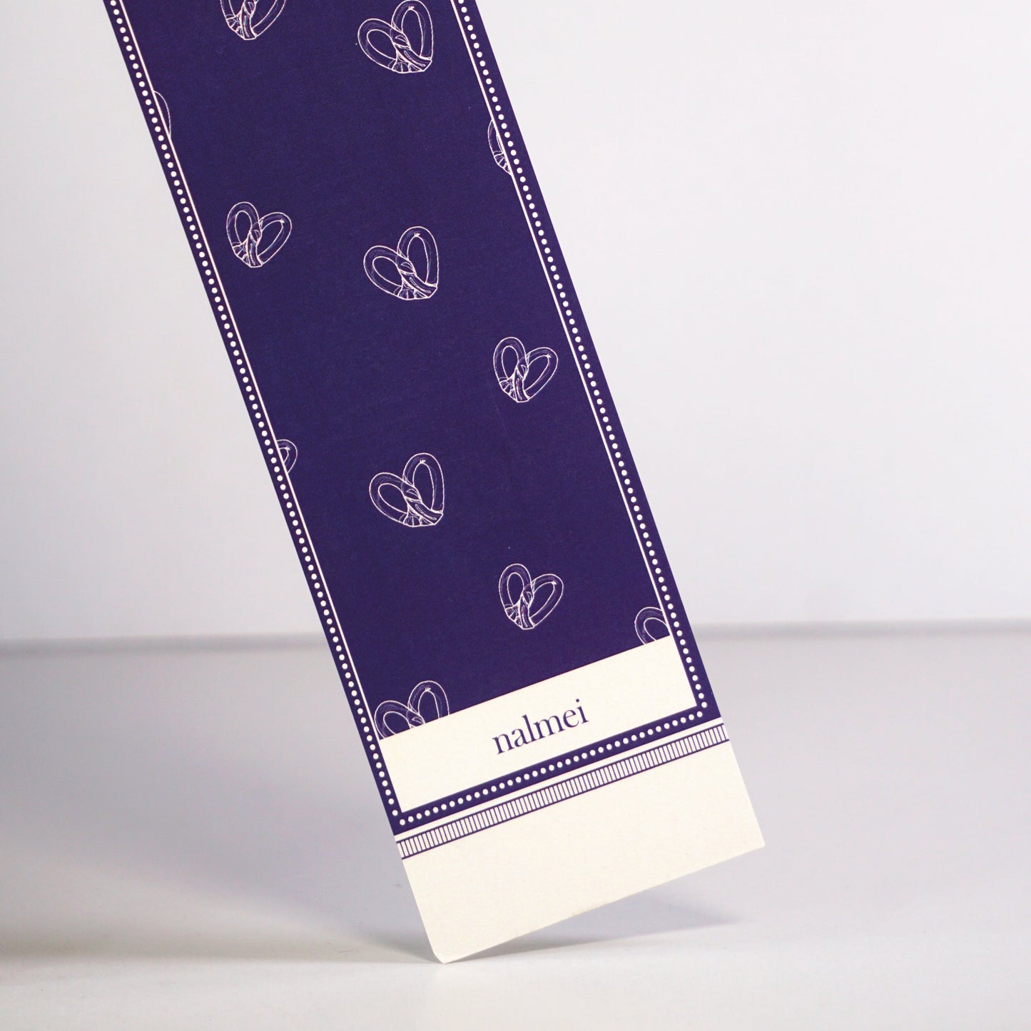 Close up of a purple and beige large bookmark with pretzel illustrations| Nalmei
